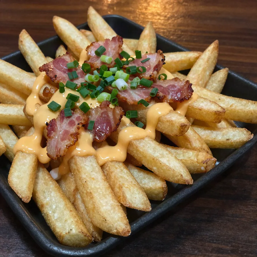 Papas rústicas con cheddar derretido, panceta crocante y verdeo.